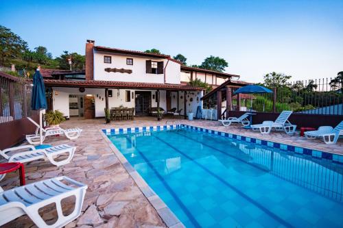 阿蒂巴亞的住宿－Alameda Galu，一个带椅子的游泳池以及一座房子