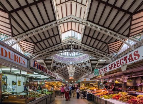 a market with people walking through a market with fruits and vegetables at Veronica Center Room in Valencia