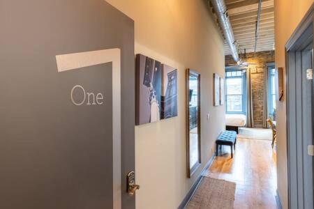 a hallway with a door to a room with pictures on the wall at Hip Urban Loft - Small Town Charm - 124 LOFTS #1 in West Dundee