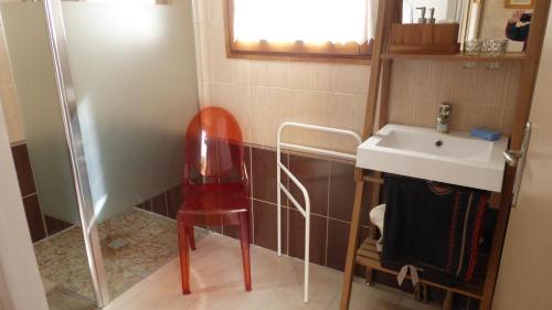 La salle de bains est pourvue d'une chaise rouge à côté d'un lavabo. dans l'établissement Abrikota, à Saint-Christophe-du-Jambet