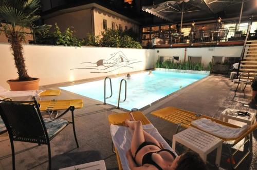 Eine Frau, die auf einem Stuhl neben einem Pool liegt. in der Unterkunft Hotel Baslertor in Luzern