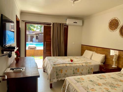 a hotel room with two beds and a television at Pousada Paraíso dos Milagres in São Miguel dos Milagres