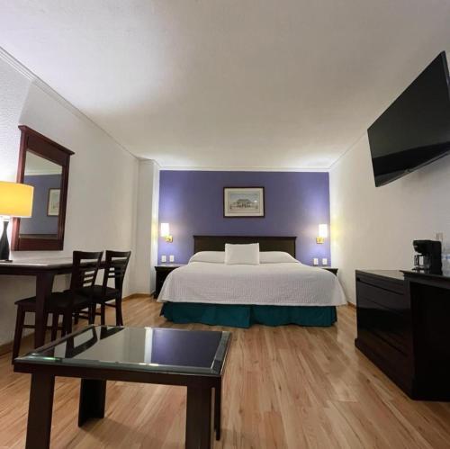 サカテカスにあるHotel Arroyo de la Plataのベッドとテーブルが備わるホテルルームです。