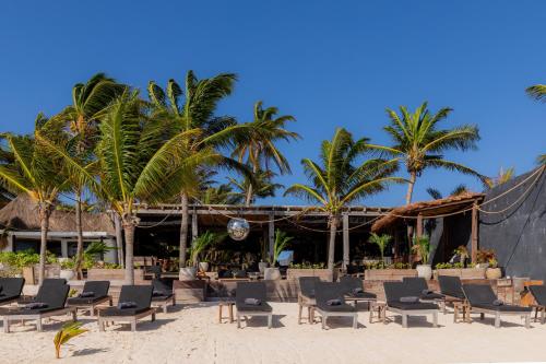 a group of chairs and palm trees on a beach at Casa Gitano in Tulum