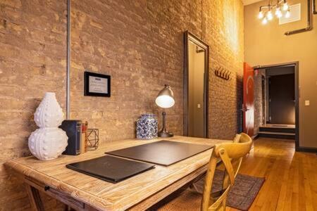 a wooden table in a room with a brick wall at Hip Urban Loft-Small Town Charm-124 LOFTS #2 in West Dundee