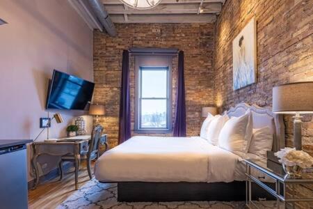 um quarto com uma cama e uma parede de tijolos em Hip Urban Loft - Small Town Charm -124 LOFTS #3 em West Dundee