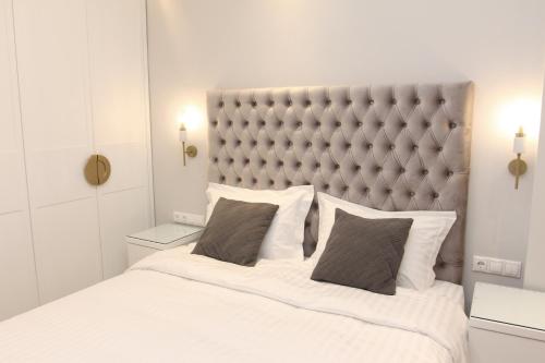 a bedroom with a large white bed with a padded headboard at central metropolis luxury living in Athens