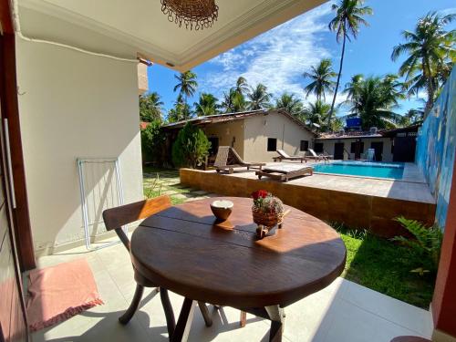 una mesa de madera en un patio con vistas a la piscina en Pousada Paraíso dos Milagres en São Miguel dos Milagres