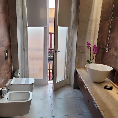 a bathroom with a sink and a toilet and a window at Palazzo Ferrucci Luxury Suites in Cagliari