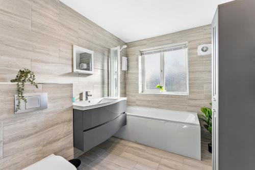 La salle de bains est pourvue d'une baignoire blanche, d'un lavabo et d'une chambre. dans l'établissement Stylish Nottingham House - Parking - Garden, à Nottingham