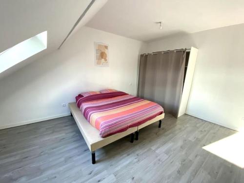 Un dormitorio con una cama con una manta a rayas. en Appartement 2chambres/PuyDuFou, en Mauléon