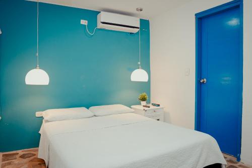 a bedroom with a blue wall and a white bed at Hotel Casamart Rodadero in Santa Marta