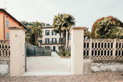 an open gate to a white house with palm trees at Gio Leo Guest House in Lesa