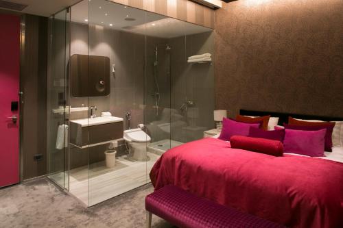 a bedroom with a large red bed and a bathroom at The Hip Hotel Santiago in Santiago