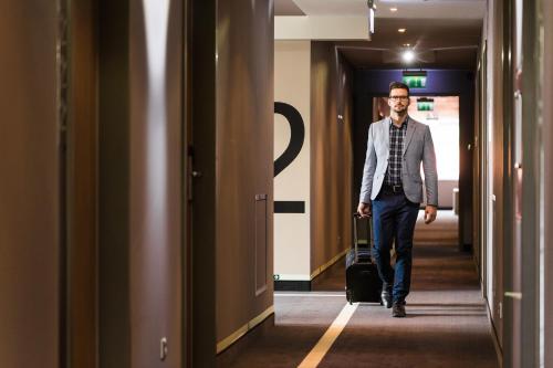 a man walking down a hallway with a suitcase at Best Western Plus Lakeside Hotel in Székesfehérvár