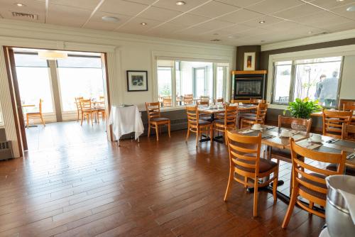 a restaurant with tables and chairs and a fireplace at Auberge le Parasol in Saguenay