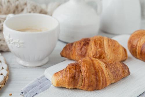 tres croissants en un plato junto a una taza de café en Bagu Villa de Mar, en Punta del Este