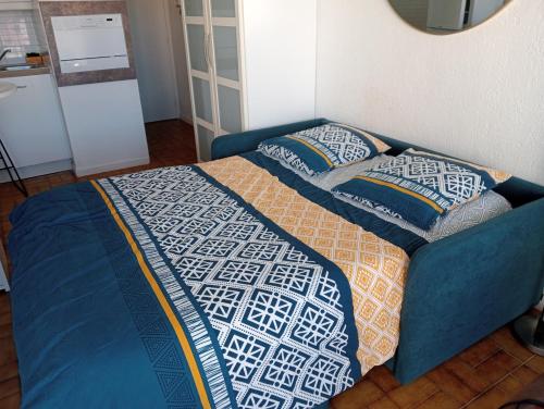 - un lit avec une couette et des oreillers bleus dans l'établissement Emplacement idéal ! Studio vue port Plages à pied !, au Cap d'Agde