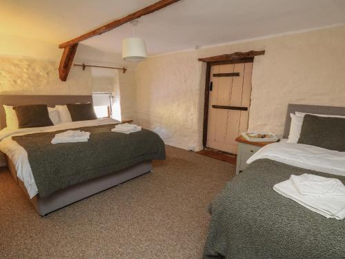 a bedroom with two beds and a door to a garage at Y Cartws in Llanybyther