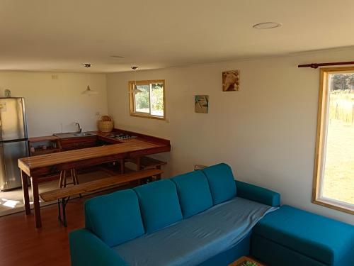 a living room with a blue couch and a table at Entre Pinos y Volcanes in Frutillar