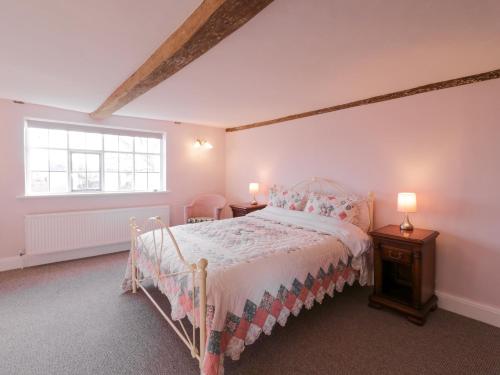 a bedroom with a bed and two tables and a window at West House Farm in Leiston