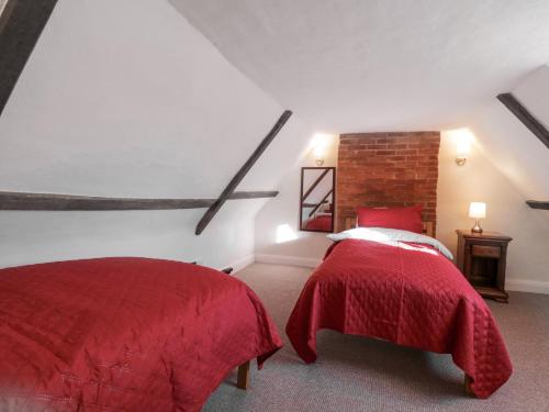 two beds in a attic bedroom with red covers at West House Farm in Leiston