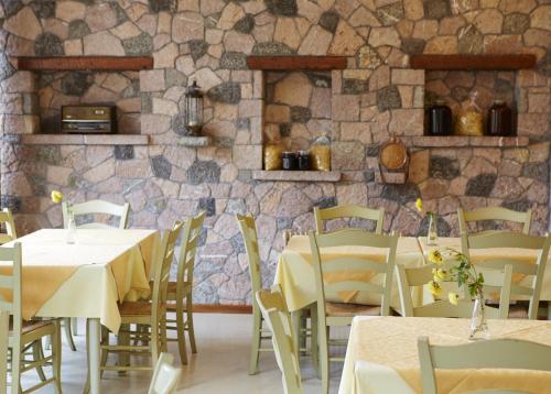 a restaurant with tables and chairs and a stone wall at To Balkoni tis Agorianis in Eptalofos
