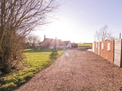 a gravel road with a building in the background at West House Farm in Leiston