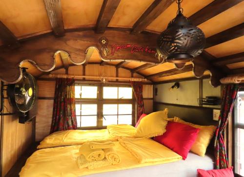 a bedroom with a bed with yellow sheets and red pillows at BellaTiny, Tiny House & Gypsy Wagon in Ondekaremba