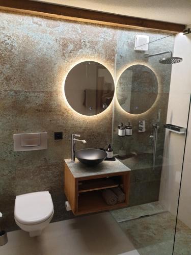 a bathroom with a sink and a toilet and a mirror at SALZANO Hotel - Spa - Restaurant in Interlaken
