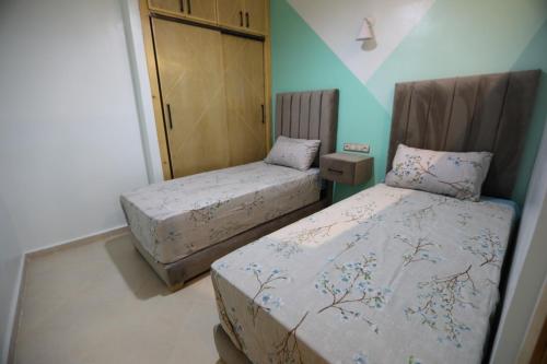 two beds in a room with blue walls at مولاي يعقوب in Fès