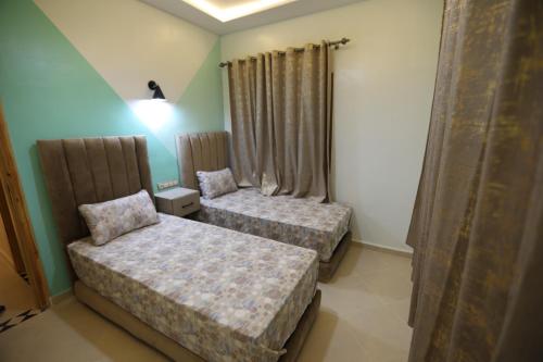 a bedroom with two beds and a lamp and curtains at مولاي يعقوب in Fez