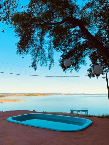 una gran piscina azul junto a un árbol en Casa Jade en Ribeirão Claro