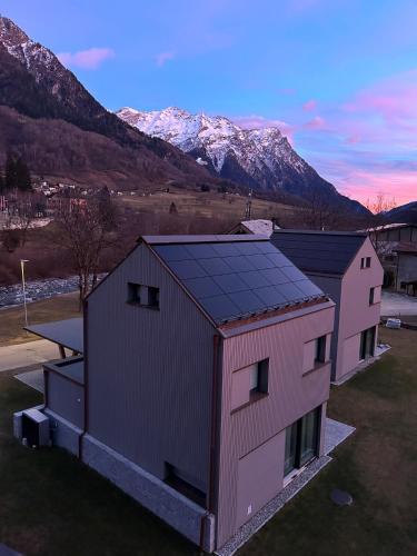 two buildings with snow covered mountains in the background at Ca' dal Nos in Olivone