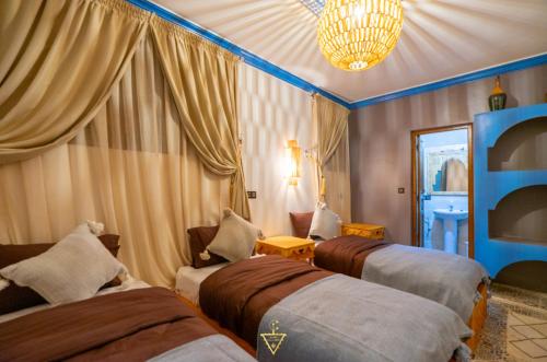 una camera con tre letti e un lampadario a braccio di Riad Village a Imlil