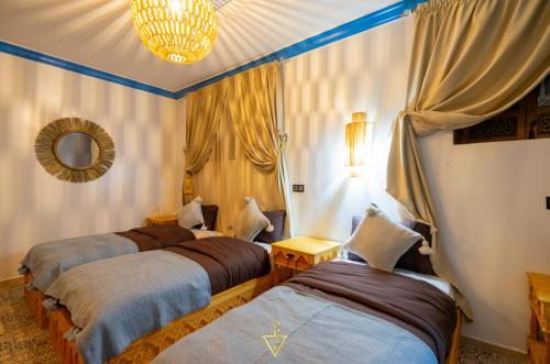 a bedroom with three beds and a mirror at Riad Village in Imlil