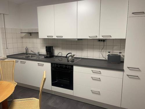 a kitchen with white cabinets and a black stove at Ferienhaus am Teutoburger Wald in Detmold
