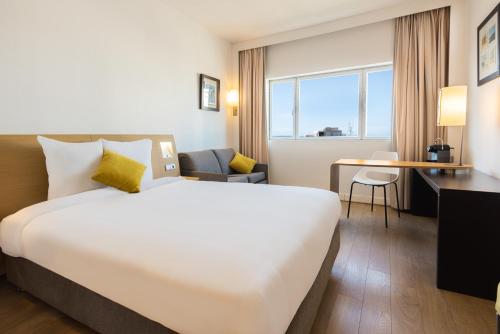 ein Hotelzimmer mit einem großen Bett und einem Schreibtisch in der Unterkunft Novotel Casablanca City Center in Casablanca