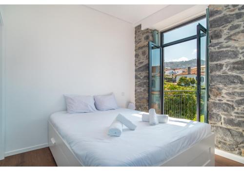 a bedroom with a white bed with a large window at Casa Lanço with Spectacular View in Funchal