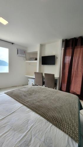 a bedroom with two chairs and a large bed at Flat Jaguanum in Mangaratiba