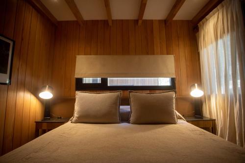 a bedroom with a bed with two pillows and two lights at Explora la magia de San Martín de los Andes in San Martín de los Andes