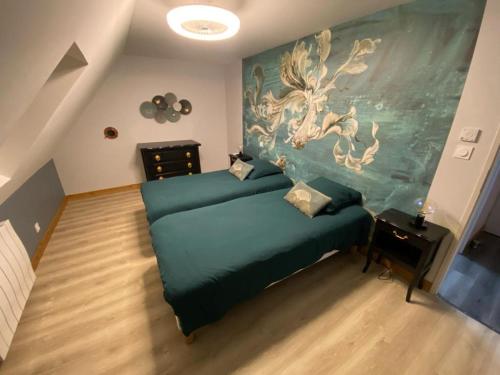 Un dormitorio con una cama verde con una pintura en la pared en Mesnil Montrivaut en Viévigne
