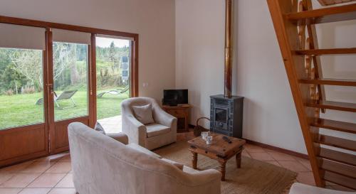 a living room with two chairs and a fireplace at Bio Quinta do Pantano, Agro Turismo in Santo António da Serra