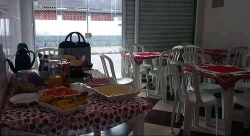une table avec des tables et des chaises rouges et blanches dans l'établissement Pousada Do Léo, à Bertioga