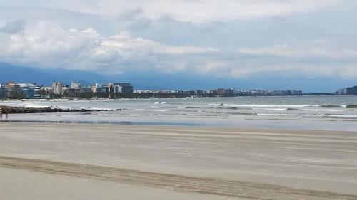 a beach with the ocean and buildings in the background at Pousada Do Léo in Bertioga