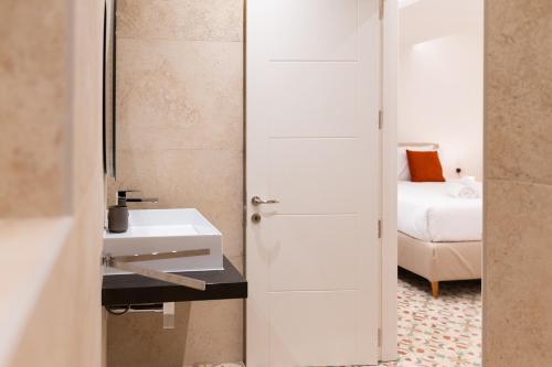 a white bathroom with a sink and a bed at Florette Suite Designer Finish with Stunning Lounge Terrace by ArcoBnb in Il-Furjana