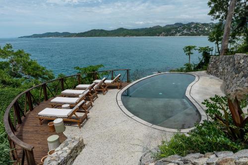 a swimming pool with lounge chairs next to the water at Tokipa at Punta Sayulita in Sayulita