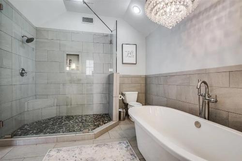 a bathroom with a tub and a toilet and a chandelier at Beautiful Farmhouse w/ pool on 6 acres ranch in Aubrey