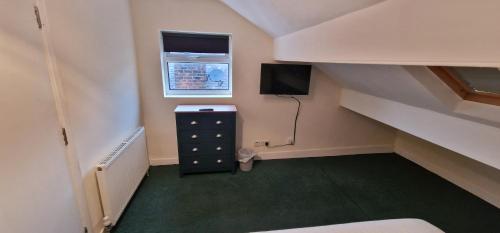 um quarto com uma escada com uma cómoda e uma televisão em ROOMS in WAKEFIELD CITY CENTRE em Wakefield