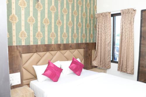 2 Betten mit rosa Kissen im Schlafzimmer in der Unterkunft HOTEL RAMJI in Karmād